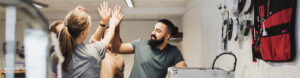 Kollegor gör high five i en verkstad med verktygsvägg