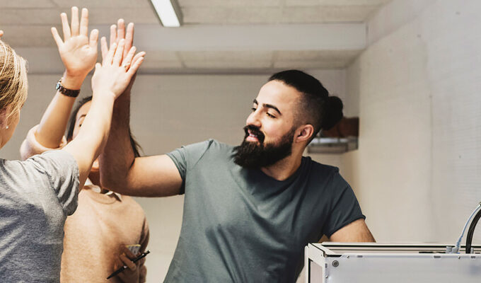Kollegor gör high five i en verkstad med verktygsvägg